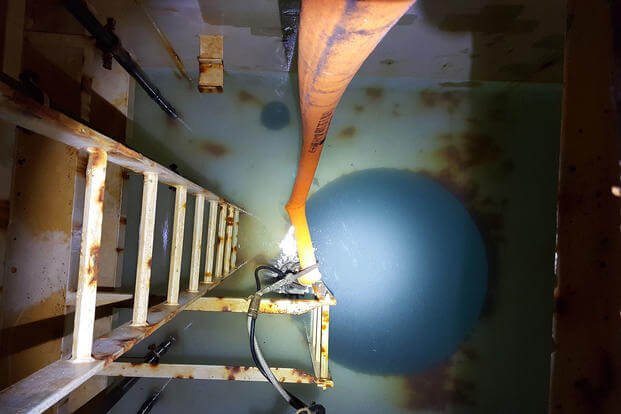 A March 15, 2016 photograph from the day of the incident and obtained by Military.com is a top down view of one of the potable water tanks on the USS Boxer. The milky substance seen in the photo is the fuel sitting on top of the water as a submersible pump dumps the contaminated water into the ship’s bilge. potable water tanks on the USS Boxer